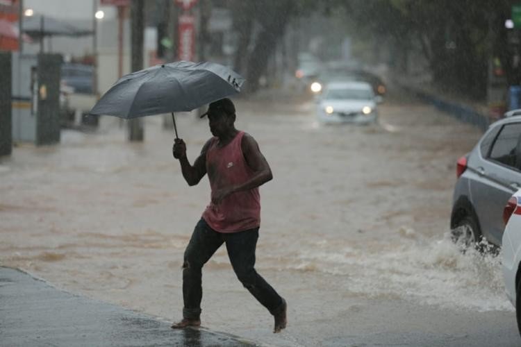 Pedestres se arriscam para atravessar pontos alagados de Salvador